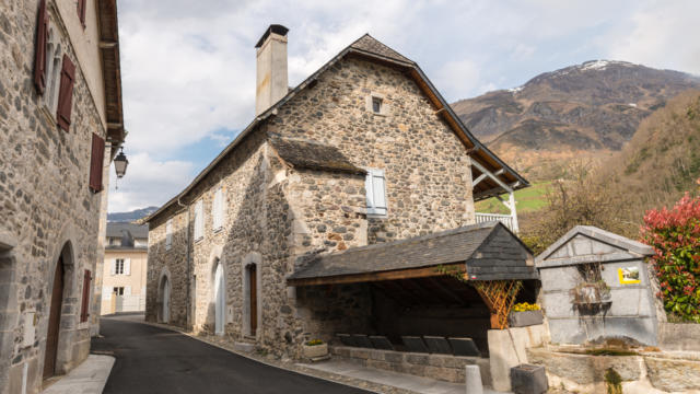 Vue sur une maison traditionnelle béarnaise dans le village médiéval de Borce avec la montagne en fond