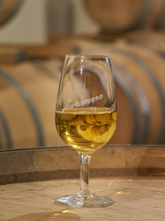 Un verre de vin de Jurançon est posé sur un tonneau dans un chai